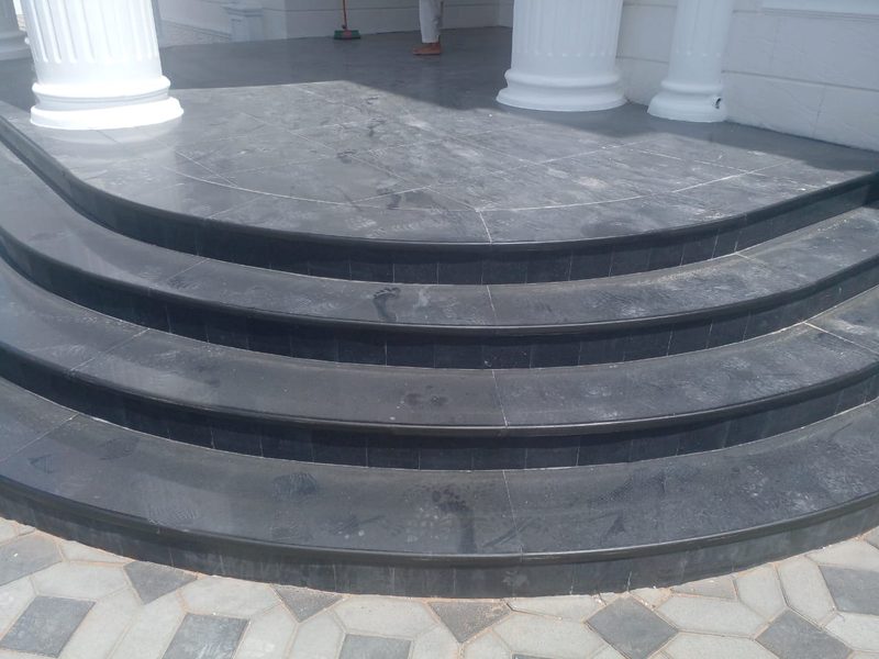 Curved granite entrance steps between rendered columns at an Al Ain villa