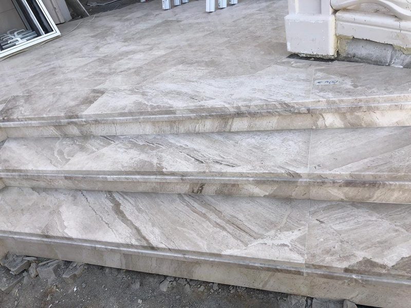 Large marble slabs laid as a terrace surface beside a rendered column — Reef Al Ghadeer, Al Ain