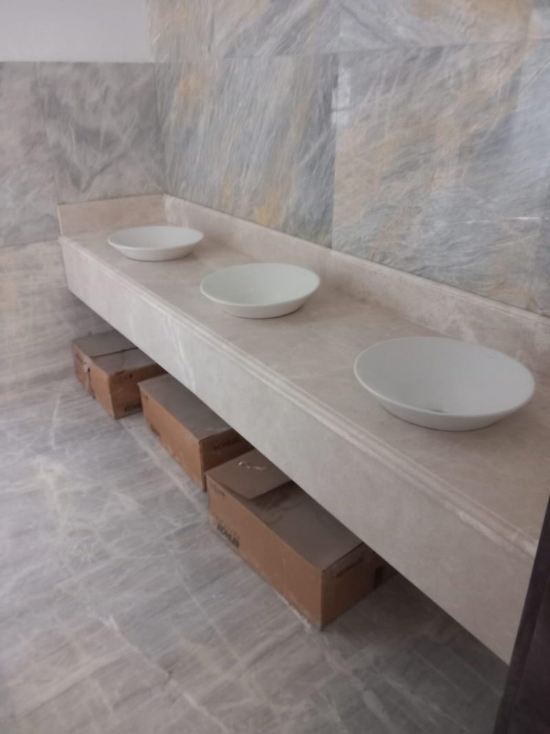 Long stone vanity with three vessel basins and open timber drawers — Reef Al Ghadeer, Al Ain