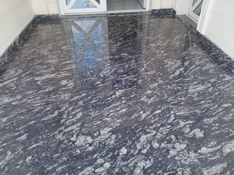 Polished dark granite floor reflecting a villa entrance doorway — Reef Al Ghadeer, Al Ain