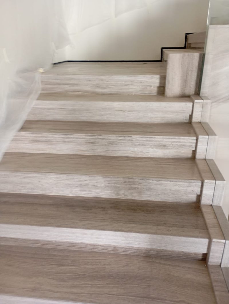 Stone staircase with frameless glass balustrade and a wide half-landing — Reef Al Ghadeer, Al Ain